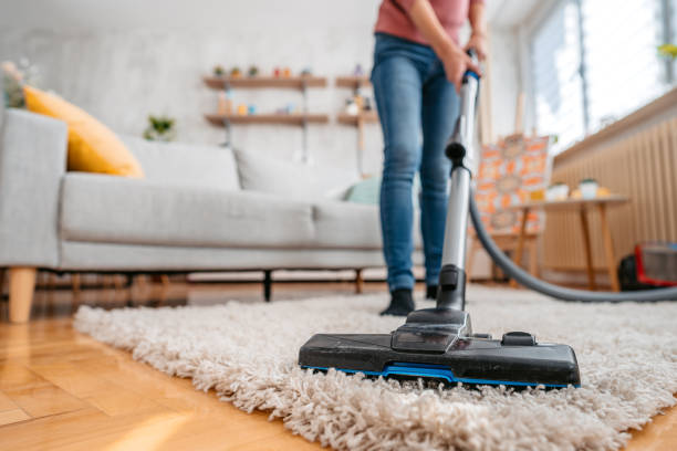 young woman vacuuming her apartment - vacuum cleaner imagens e fotografias de stock