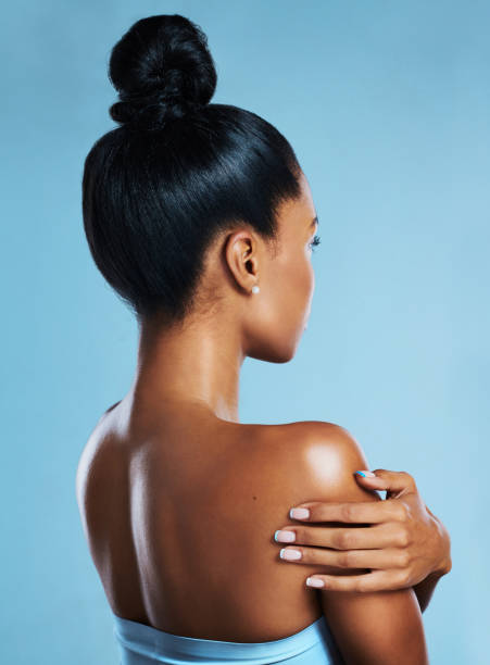 студийный снимок молодой женщины, позирующей на синем фоне - body women naked beauty стоковые фото и изображения