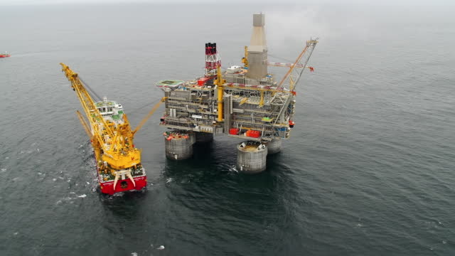 Top view of an offshore oil platform with a support vessel next to it.