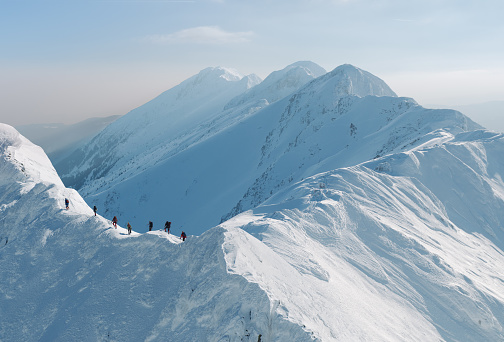 Group of mountain climbers walking on snowy mountain ridge