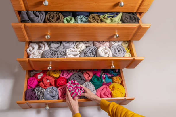 istock Cleaning and sorting clothes in the wardrobe Japanese method. Open chest drawers with  vertical storaged twisting clothes. View from above. 1392975260