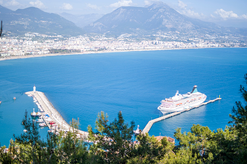 Alanya harbour, Alanya TurkeyAlanya - Antalya, Turkey, April 17th 2022: Alanya Castle is one of the symbols of Alanya, the district of Antalya. It is located on a peninsula rising approximately 250 meters from the sea. The length of its walls is 6.5 kilometers in total. The road passing through the walls was built in the settlement of Alanya, which was called Kandeleri in ancient times, during the Hellenistic period. The history of the castle, which is a 13th century Seljuk artifact, dates back to the Hellenistic period. \nThe castle was built by Seljuk Sultan Alaeddin Keykubad I, who took the city and had it rebuilt in 1221. There are 83 towers and 140 bastions in the castle. In the Middle Ages, about 1200 cisterns were built to meet the water needs of the city, which was inside the walls. Some of the cisterns are still in use. The walls were built in a planned manner, passing the Tophane and Tersane, and ending in Kızılkule, following Ehmedek, İçkale, Adam Atacak, Cilvarda cape, Arap Evliyası and Esat Bastion.