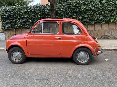 An old, vintage FIAT 500 automobile is parked outside in Rome, Italy. No people.