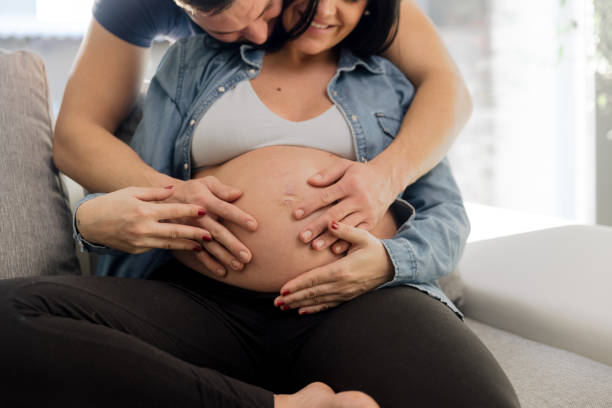 istock Man spending leisure time with pregnant wife on sofa 1392977985