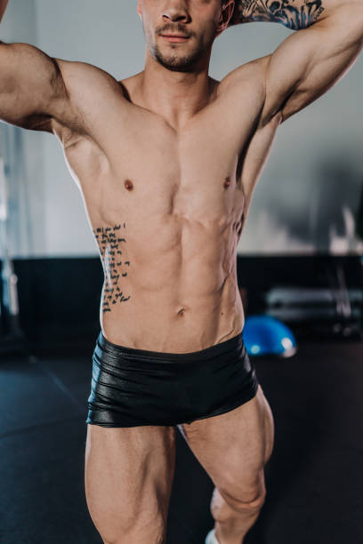 istock Midsection of handsome young man flexing muscles while exercising at gym 1392978357