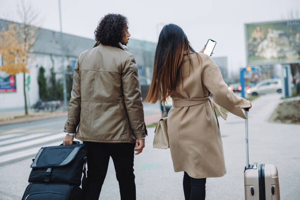 istock Two Colleagues on a business trip, walking on a sidewalk while carrying hand luggage 1392980704