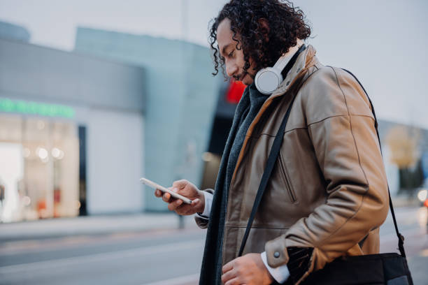 istock Businessman smiling while using his phone, standing on a sidewalk in the evening 1392981856