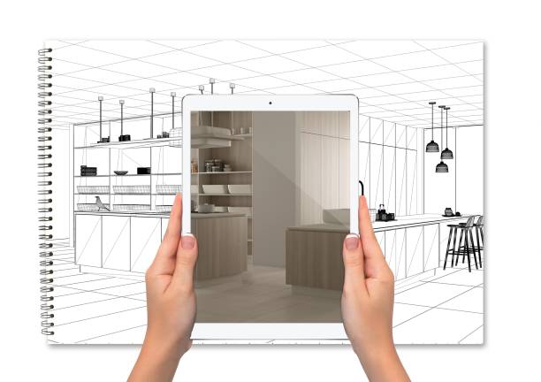 istock Hands holding tablet showing kitchen, notebook with blueprint sketch in the background, augmented reality concept, application to simulate furniture and interior design products 1392982592