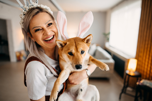Woman holds her dog in her arms and they celebrate Easter together