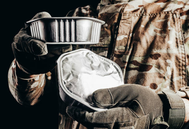 Soldier in tactical gloves holding canned food. stock photo