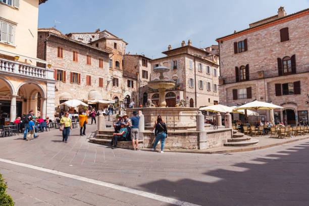 ancient fountain and people in the piazza del comune of the small town of assisi, umbria, italy. tourists in a square in assisi. - editorial built structure fountain town square imagens e fotografias de stock