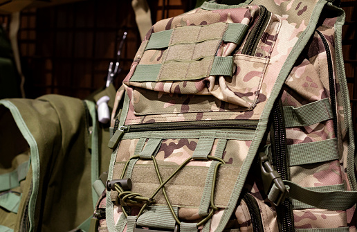 Close-up photo of camouflaged soldier backpack hanging on store stand.