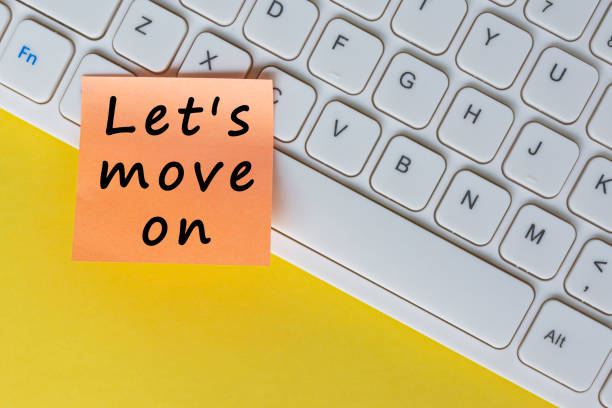 istock Let's move on text on orange sticky note on top of white keyboard. 1392985585