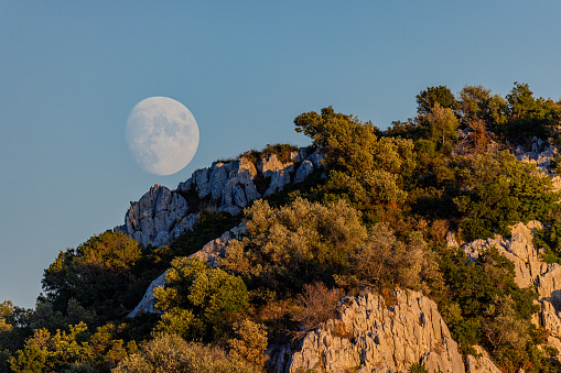 Moon with stars rising from the horizon above the hilly landscape. My astronomy work.