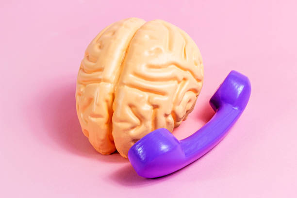 istock Human brain using dial phone on light pink background. Phone addiction, support service call, social problems concepts 1392988558