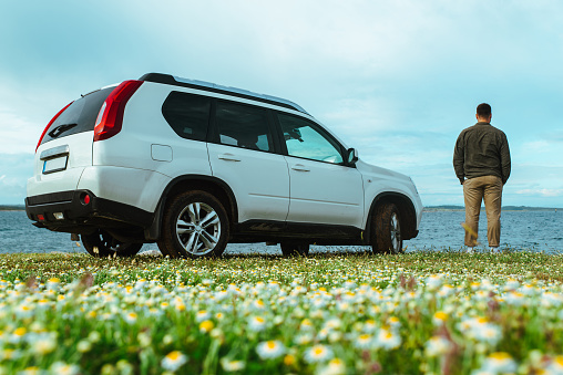 man standing near car at seaside. road trip concept. summer vacation