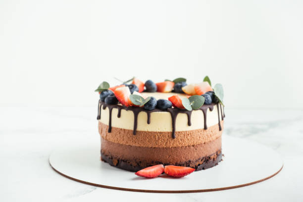 istock Brown layered cake Three chocolates decorated with bluberries, strawberries and chocolate drips on top. 1392989580