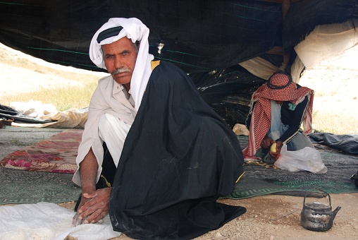 Bedouin in traditional clothes making flatbread on the fire, living in a tent in the Negev desert in Israel, Mitzpe Ramon in Israel