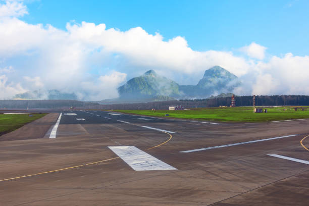 구름으로 덮인 산을 배경으로 공항의 활주로의 교차로. - runway airport airfield asphalt 뉴스 사진 이미지