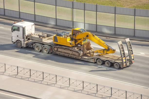 excavator being transported by a truck
