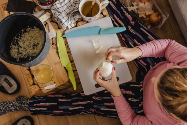 istock Woman peeling onion while sitting on floor at home 1392996135