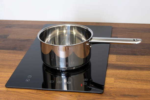 istock Saucepan ladle on an induction hob built into a wooden kitchen worktop. 1392996178
