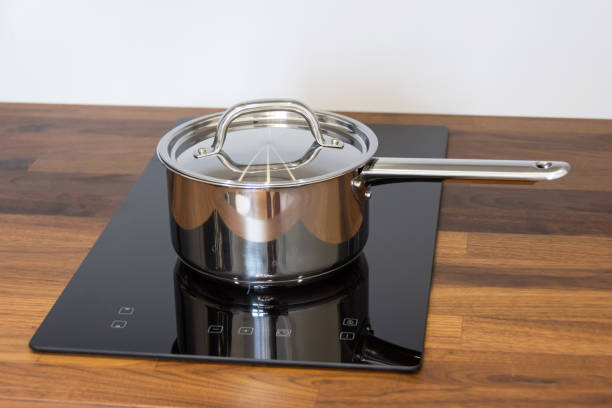 istock Saucepan ladle with lid on an induction hob built into a wooden kitchen worktop. 1392996185
