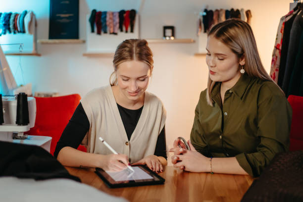 jovem olhando para alfaiate feminino trabalhando em tablet digital em oficina - hardware store store work tool customer - fotografias e filmes do acervo