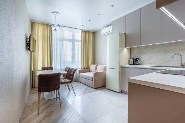 istock Modern beige and gray stylish kitchen with a table, soft chairs, a sofa and a beige refrigerator. Floor tiles and laminate. Built in household appliance 1392997905
