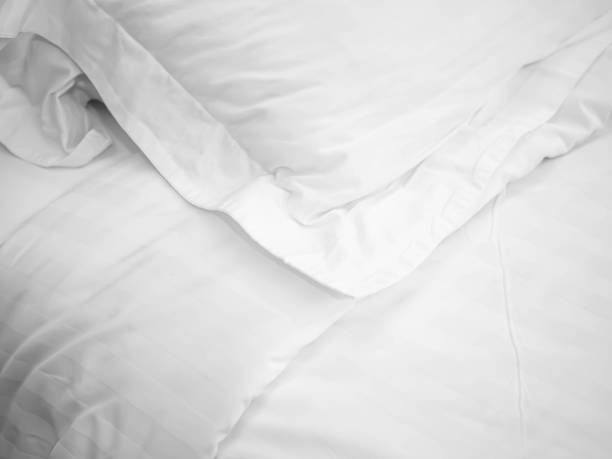 Closeup of wrinkle pillow and blanket on bed in bedroom for room service in hotel, housekeeping, homework preparing or allergy protection concept stock photo