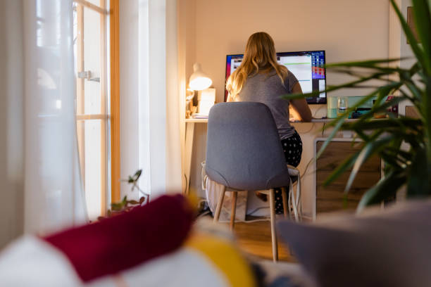 istock Rear view of female freelancer working on computer at illuminated desk 1392999250