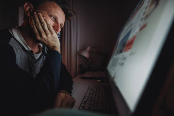 istock Tired male freelancer staring at computer while working in dark at home 1392999281