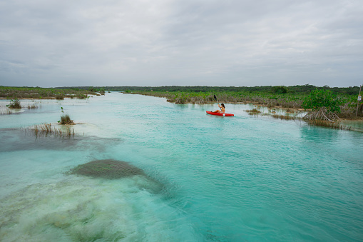 Young Caucasian woman canoeing in Bacalar Lagoon in Mexico