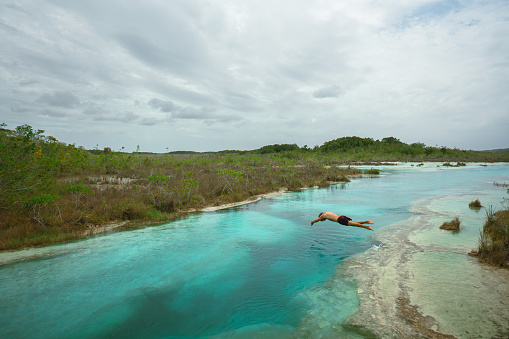 Young Caucasian man swimming in Bacalar Lagoon in Mexico