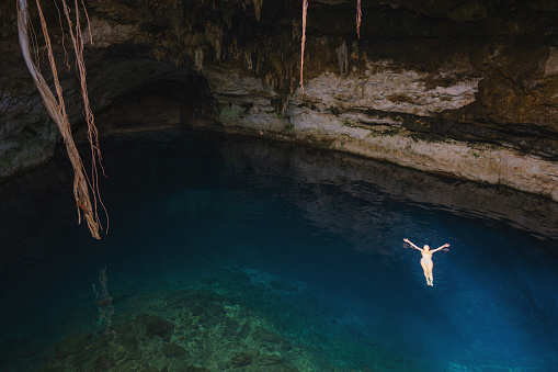 Young Caucasian woman swimming in Cenote in Yucatan, Mexico