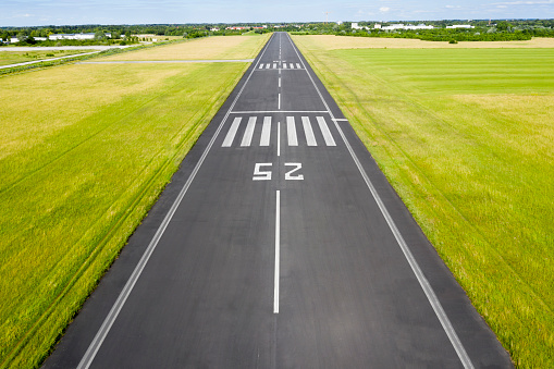 Aerial view of an airport runway with the direction marking 25 (250 degrees).