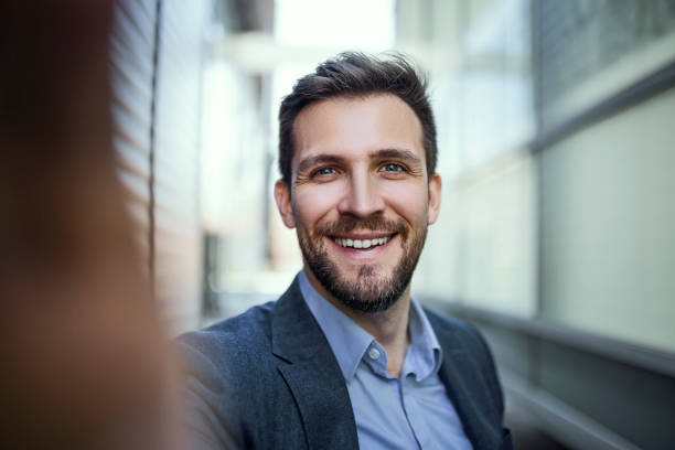 Young businessman looking at camera making selfie