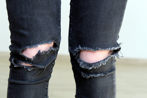 Legs in black jeans with torn knees.