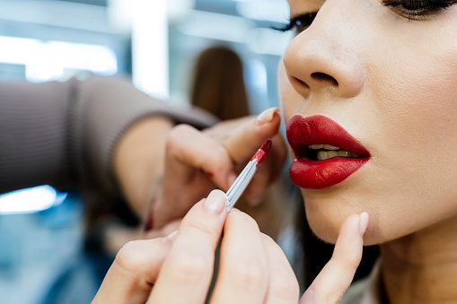 Beautiful brunette woman has lips painted in a beauty salon.