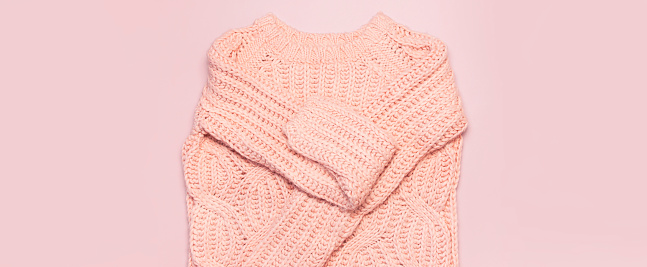 Female pink knitted sweater pullover on pastel pink background top view flat lay. Fashion Lady Clothes Set Trendy Cozy Knit Jumper Autumn winter clothes Female fashion look Lifestyle gentle background
