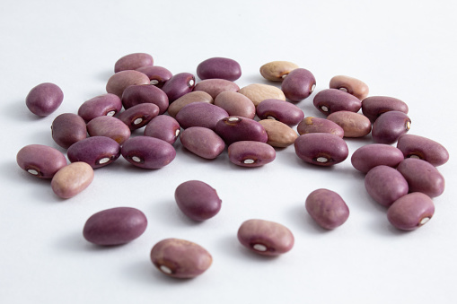 Portion of kidney beans still raw, fresh and healthy. Variety of Phaseolus vulgaris beans isolated on white background, brazilian purple beans