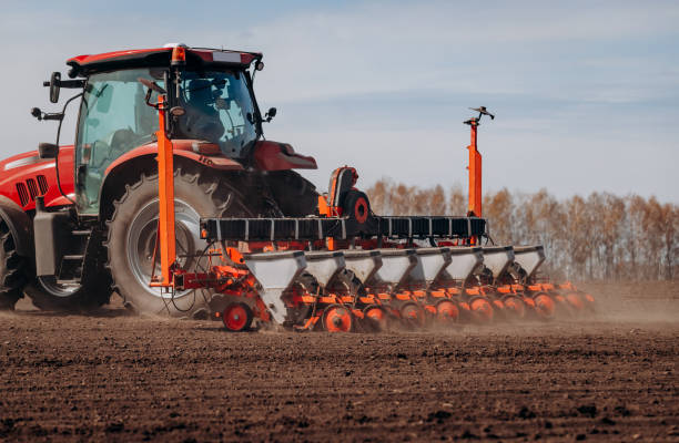 istock Spring sowing season. Farmer with a tractor sows corn seeds on his field. Planting corn with trailed planter. Farming seeding. The concept of agriculture and agricultural machinery. 1393017241