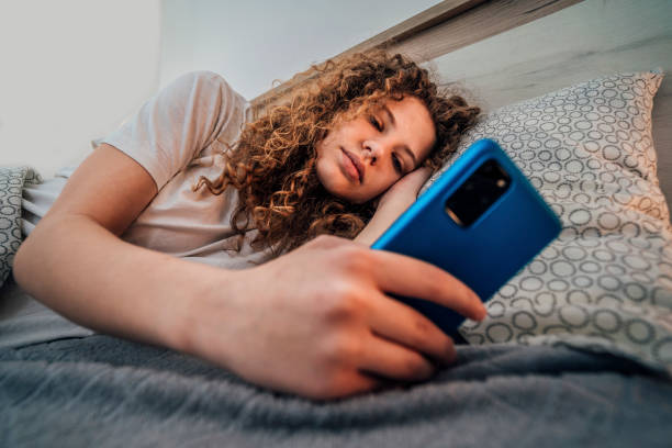 istock Young woman checking phone in bed 1393018565