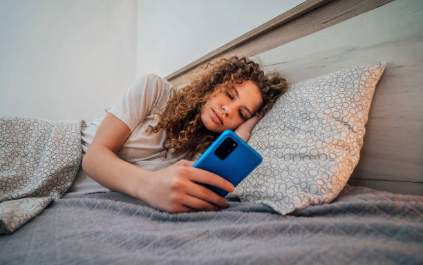 istock Young woman checking phone in bed 1393019273