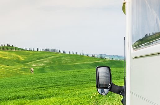 Green fields landscape background with motor home copy space, Tuscany. Travel adventure vacation.