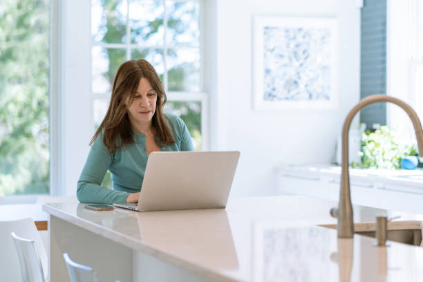 istock Mature latin woman using computer at home 1393023378