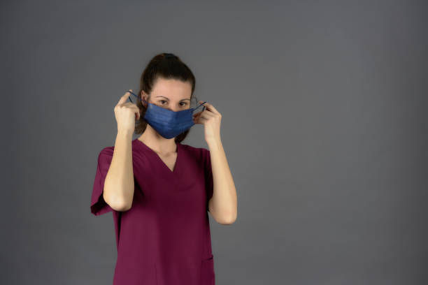 istock nurse in purple scrubs while removing surgical mask 1393025172