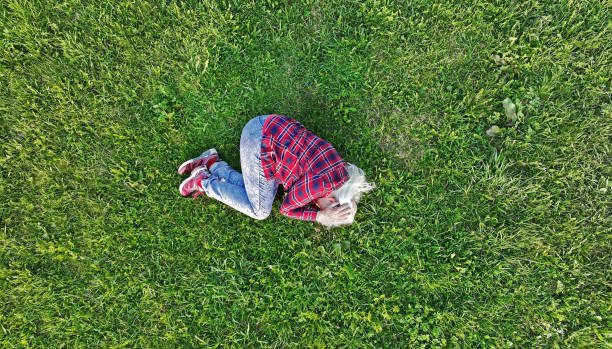Burnout - A woman lies sad and powerless on a meadow Burnout - A woman lies sad and powerless on a meadow lying on side stock pictures, royalty-free photos & images