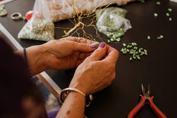 Close up shot of unrecognizable female hands, crafting golden tree, making small decoration