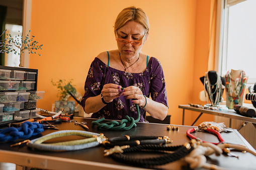 Senior woman making hand made necklaces, small business ideas.